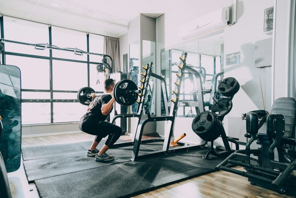 man in black shirt and blue denim jeans sitting on black exercise equipment